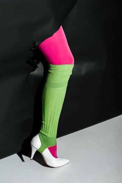ピンクのタイツ 緑色のゲートル 黒い紙を白いハイヒールで脚を見せて女性のトリミングされた画像 — ストック写真