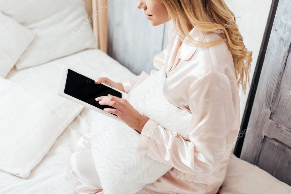 partial view of blonde woman using digital tablet with blank screen in bed during morning time at home