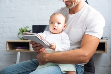 bir bebek kızı ile oturan ve evde defter tutan baba kırpılmış görünümü