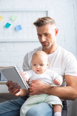 Bebek kızı ile oturan ve evde defter tutan yakışıklı babası