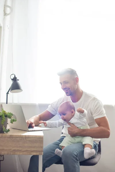 Lycklig Far Sitter Stol Håller Baby Dotter Och Använder Bärbar — Stockfoto