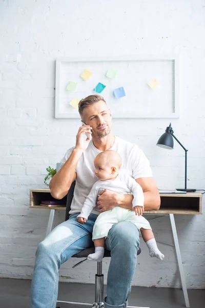 Vader Zittend Een Stoel Praten Smartphone Schattige Baby Dochter Thuis — Stockfoto