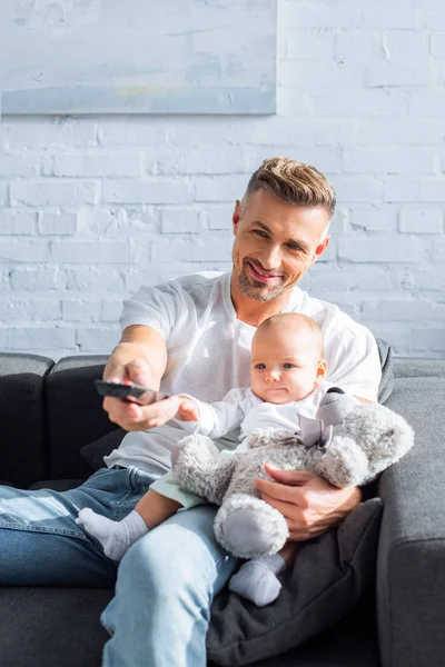 Gelukkig Vader Zittend Bank Met Baby Dochter Holding Van Afstandsbediening — Stockfoto