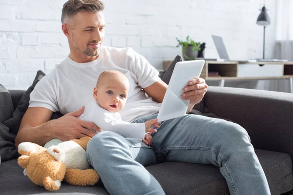 Pai Sentado Sofá Com Adorável Bebê Filha Usando Tablet Digital — Fotografia de Stock