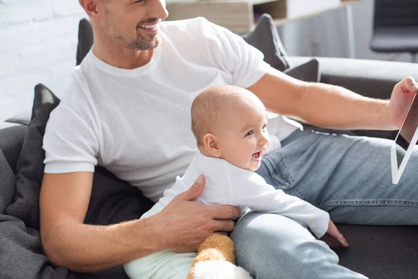 Lykkelig Far Som Sitter Sofaen Med Leende Datter Bruker Digital – stockfoto