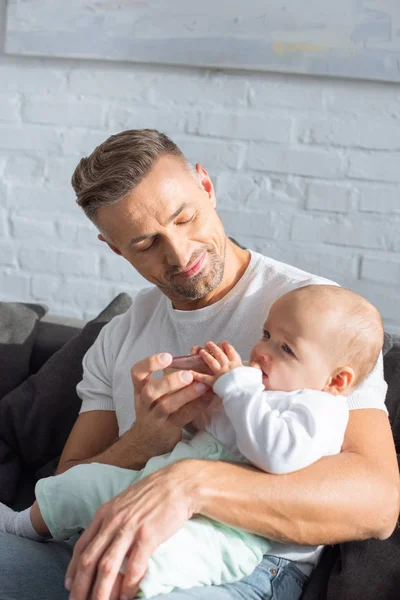 Stilig Far Sitter Soffan Och Utfodring Baby Dotter Hemma — Stockfoto