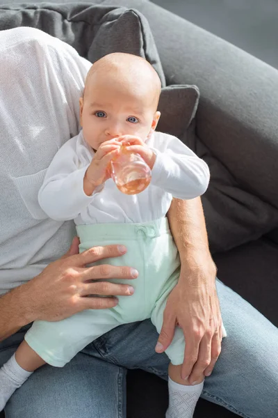 Ayah Duduk Sofa Dan Menggendong Bayi Menggemaskan Dengan Botol Rumah — Stok Foto