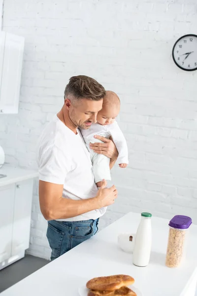 Vader Holding Baby Dochter Kijken Naar Tabel Met Voedsel Fles — Gratis stockfoto