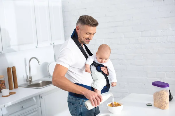 Father Holding Infant Daughter Baby Carrier Pouring Milk Bowl Cornflakes — Stock Photo, Image