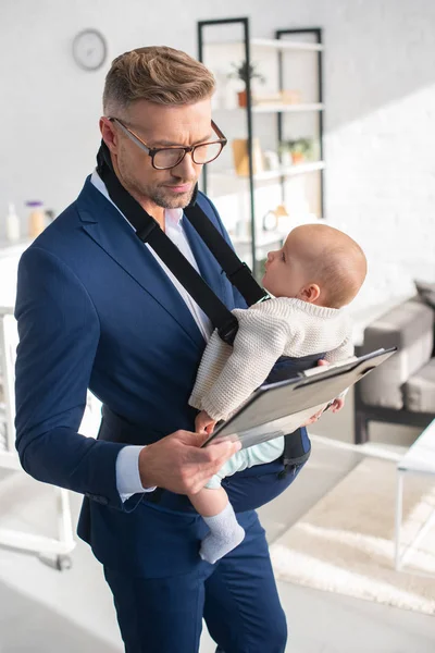 Thoughtful Businessman Holding Clipboard Infant Daughter Baby Carrier — Stock Photo, Image