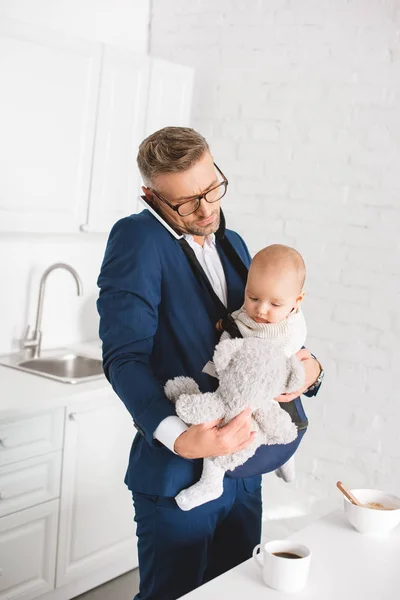 Handsome Businessman Holding Infant Daughter Teddy Bear While Talking Smartphone — Stock Photo, Image