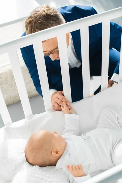 Lycklig Far Högtidskläder Håller Hand Nyfödda Dotter Spjälsängen — Gratis stockfoto