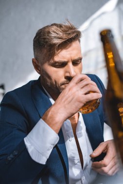 selective focus of businessman holding glass and drinking whiskey  clipart