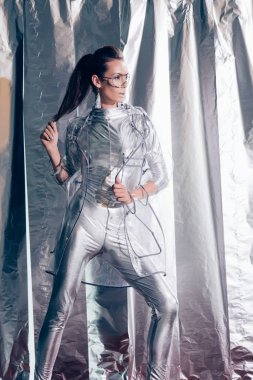 güzel genç model gümüş elbise ve yağmurluk Metalik arka plan üzerinde poz