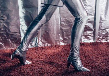 partial view of model posing in silver bodysuit and footwear on metallic background clipart
