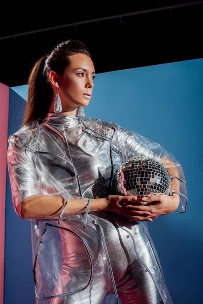 Fashionable Girl Silver Bodysuit Raincoat Posing Disco Ball Blue Background — Free Stock Photo