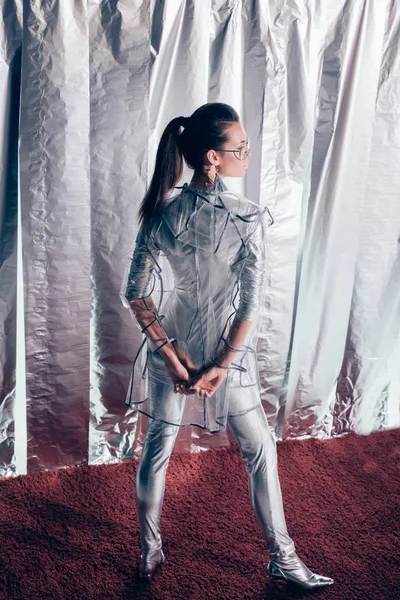 Baksidan Fashionabla Kvinna Poserar Silver Bodysuit Och Regnrock Metalliska Bakgrund — Gratis stockfoto