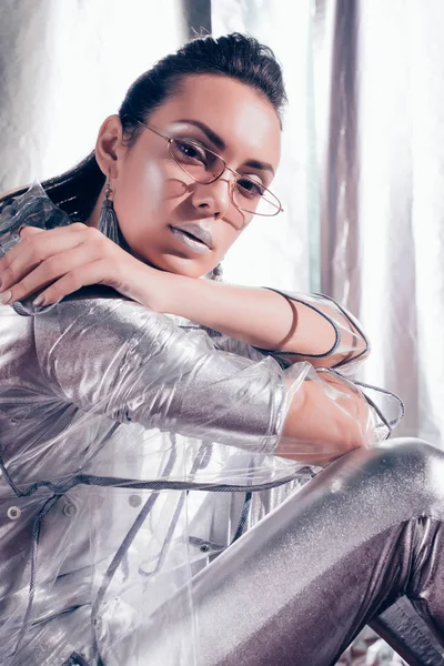 Fashionable Girl Posing Trendy Glasses Silver Bodysuit Raincoat Metallic Background — Free Stock Photo