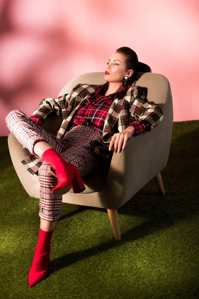 Vacker Brunett Kvinna Rutig Kostym Poserar Fåtölj Rosa Bakgrund — Gratis stockfoto