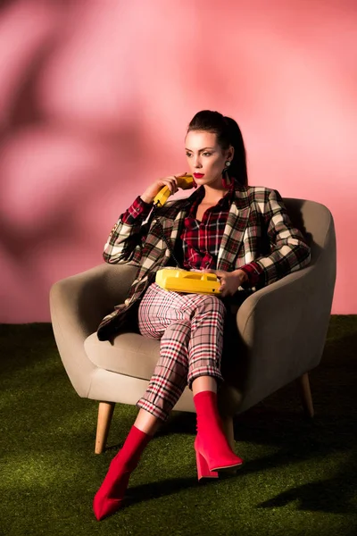 Aantrekkelijke Vrouw Geruite Pak Poseren Fauteuil Met Roterende Telefoon Roze — Stockfoto