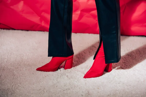 妇女摆在红色高跟鞋和黑色皮裤的部分看法 — 图库照片