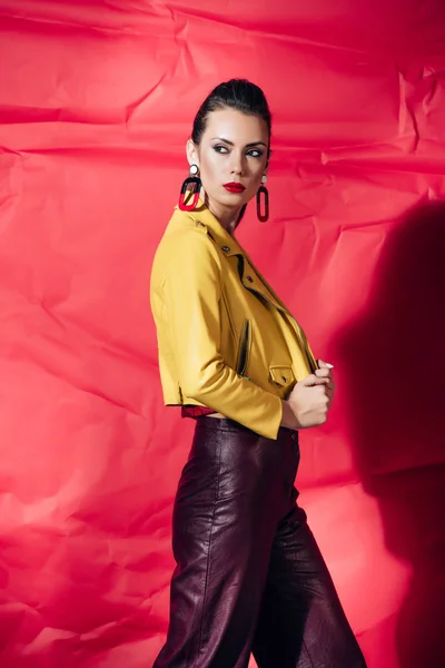 Bela Mulher Elegante Posando Jaqueta Couro Amarelo Fundo Vermelho — Fotografia de Stock