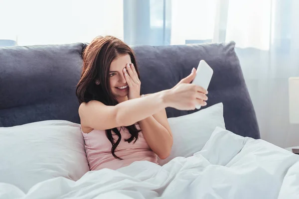 Tersenyum Gadis Mengambil Selfie Smartphone Sambil Duduk Tempat Tidur Selama — Stok Foto