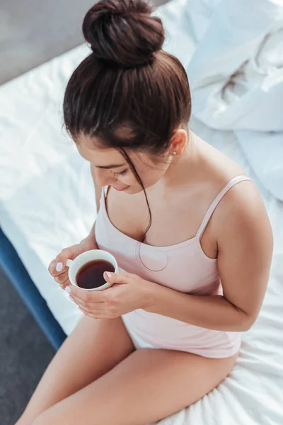 Μεγάλη Γωνία Προβολής Νεαρή Γυναίκα Κάθεται Φλιτζάνι Καφέ Στο Κρεβάτι — Δωρεάν Φωτογραφία