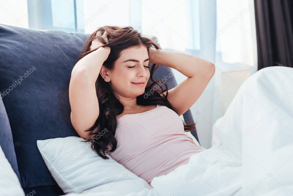 cheerful pretty girl waking up on bed during morning time at home