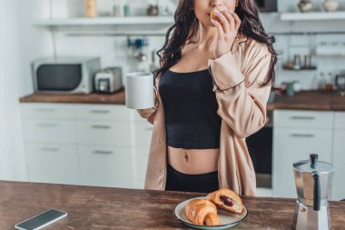 Kahvaltı croissants ve kahve ile evde mutfak ahşap masada kadının kısmi görünümü