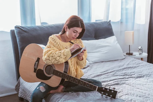 Beautiful Girl Sitting Acoustic Guitar Writing Song Textbook Bed Home — Free Stock Photo