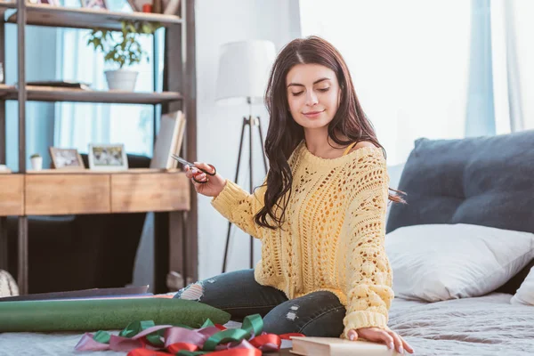 Pretty Girl Packing Christmas Gift While Sitting Bed Home — Free Stock Photo