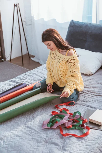 Attraente Ragazza Imballaggio Regalo Natale Mentre Seduto Sul Letto Casa — Foto stock gratuita