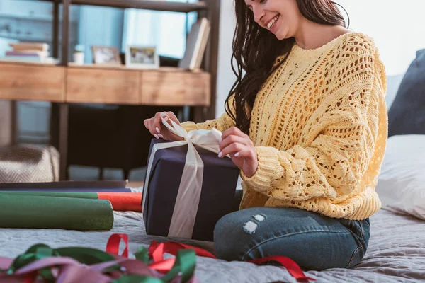 Счастливая Молодая Женщина Обертывает Подарочную Коробку Праздничной Лентой Сидя Дома — Бесплатное стоковое фото