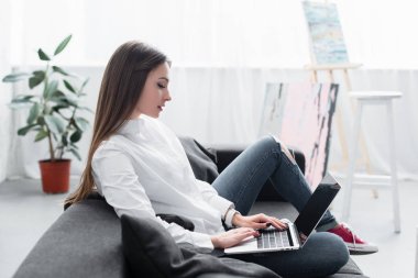 seçici odak bir kanepede oturan ve oturma odasında dizüstü kullanarak kız