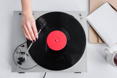 cropped view of woman playing vinyl record on vintage player clipart
