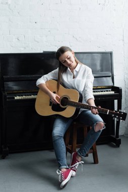 kız oturma ve gitar oturma odasında piyano ile arka plan üzerinde beyaz gömlekli