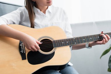 Kırpılan oturan ve gitar çalmak oturma odasında kız görünümünü
