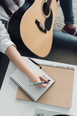 Not defterinde müziklerin yazarken yazma akustik gitar ile kızın kırpılmış görünümü