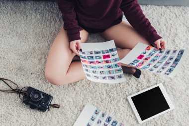 halı üzerinde oturan ve resimler tutan fotoğrafçı kırpılmış görünümü