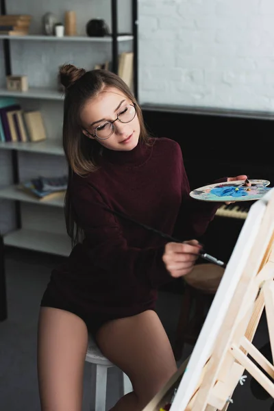 Menina Bonita Camisola Borgonha Óculos Sentados Segurando Paleta Pintura Casa — Fotografia de Stock
