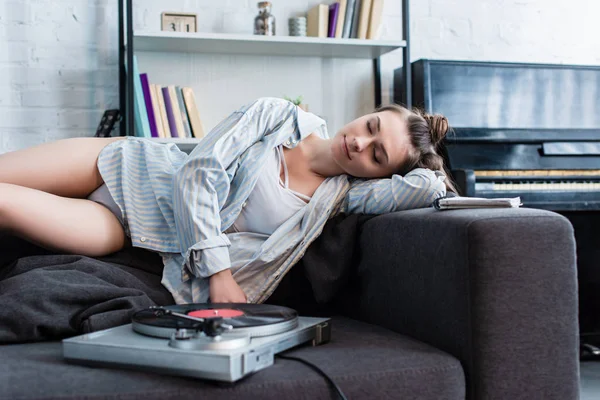 シャツと下着ヴィンテージのレコード プレーヤーを自宅近くのソファで眠っている魅力的な女の子 — ストック写真