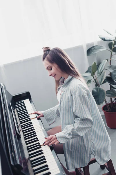 美丽的音乐家弹钢琴和微笑在客厅 — 图库照片
