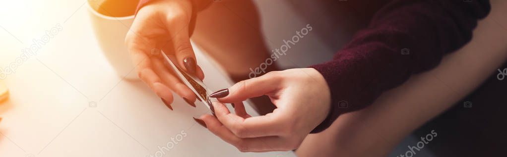 partial view of girl sitting and rolling marijuana joint at home 