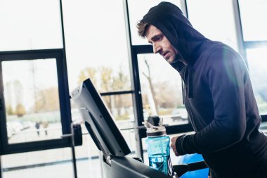 yakışıklı sporcu spor salonunda treadmill egzersiz hoodie yan görünüm 