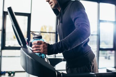 sporcu treadmill egzersiz ve spor salonunda spor şişe tutan hoodie içinde kırpılmış görüntü 