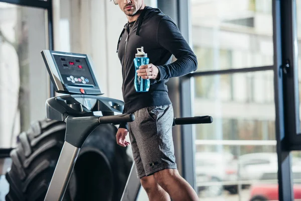 运动员在跑步机上锻炼和拿着运动瓶在健身房的头套的形象 — 图库照片
