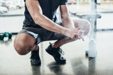 cropped image of sportsman applying talcum powder on hands before training in gym clipart
