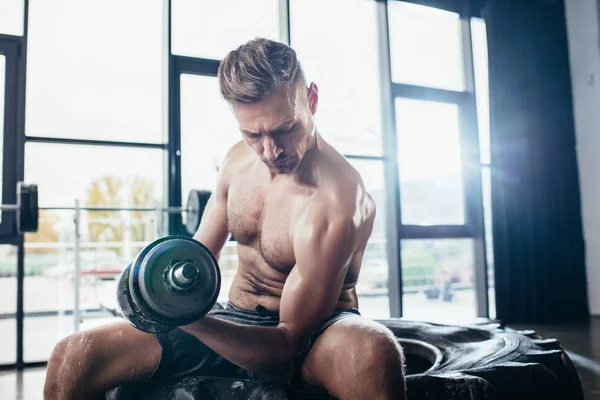 Bonito Sem Camisa Desportista Sentado Pneu Exercitando Com Dumbbell Ginásio — Fotografia de Stock