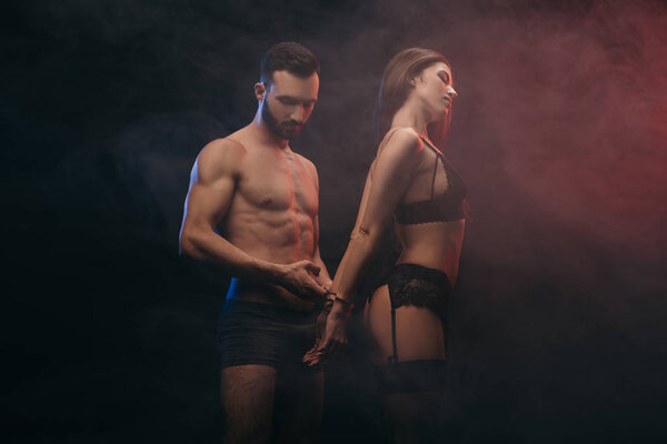 beautiful erotic couple with handcuffs in smoky room